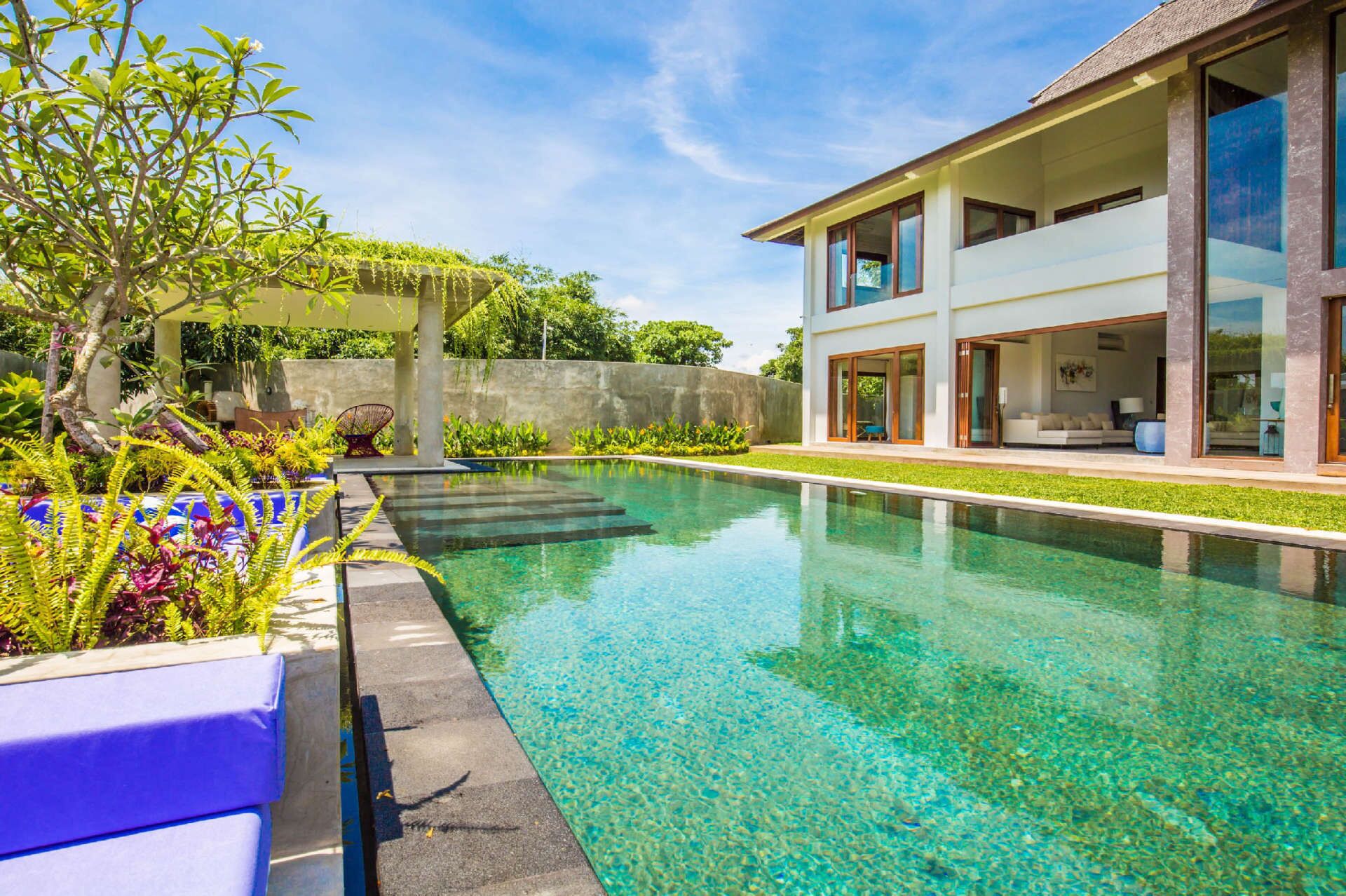 Ein modernes Haus mit Swimmingpool, überdachter Außenbereich und üppiger Bepflanzung.