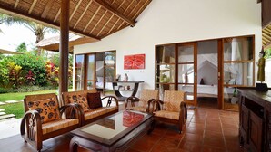 A spacious patio with wooden furniture, a glass-top coffee table, and a bed with a canopy. - Luxury Villa in Bali near Beach, Bali Villa 2031 (Ubud)