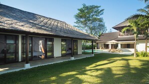 A modern villa with a thatched roof, a swimming pool, and a well-maintained lawn. - Luxury Villa in Bali near Beach, Bali Villa 2036 (Ubud)