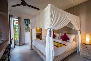 A four-poster canopy bed with a wooden frame, white bedding, and a decorative pillow.