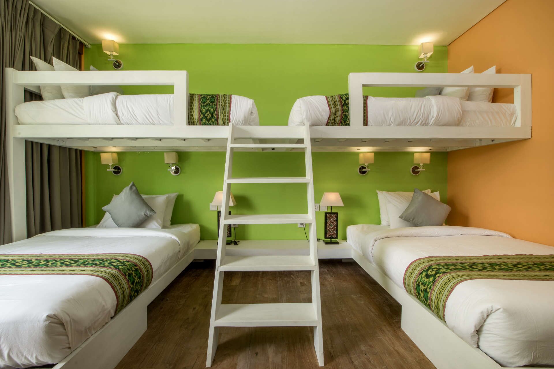 Une pièce avec deux lits superposés, une échelle et un mur vert.