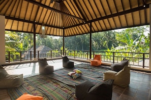 A covered outdoor seating area with a view of lush greenery.