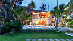 A two-story house with a swimming pool, surrounded by lush greenery and palm trees. - Villa for Rent in Bali 2002 (Manggis)