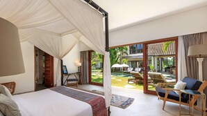 Un dormitorio con cama con dosel, un escritorio con silla, y vistas a una piscina y zona de estar al aire libre.