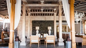 A covered outdoor seating area with stone walls, wooden furniture, and a stone fireplace. - Luxury 12 Bedroom Villa With Private Pool, Bali Villa 2027 (Kerobokan)