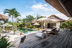 A wooden deck with lounge chairs and a pool, surrounded by tropical plants and thatched-roof structures. - Beautiful Villa With Private Pool, Bali Villa 2029 (Canggu)