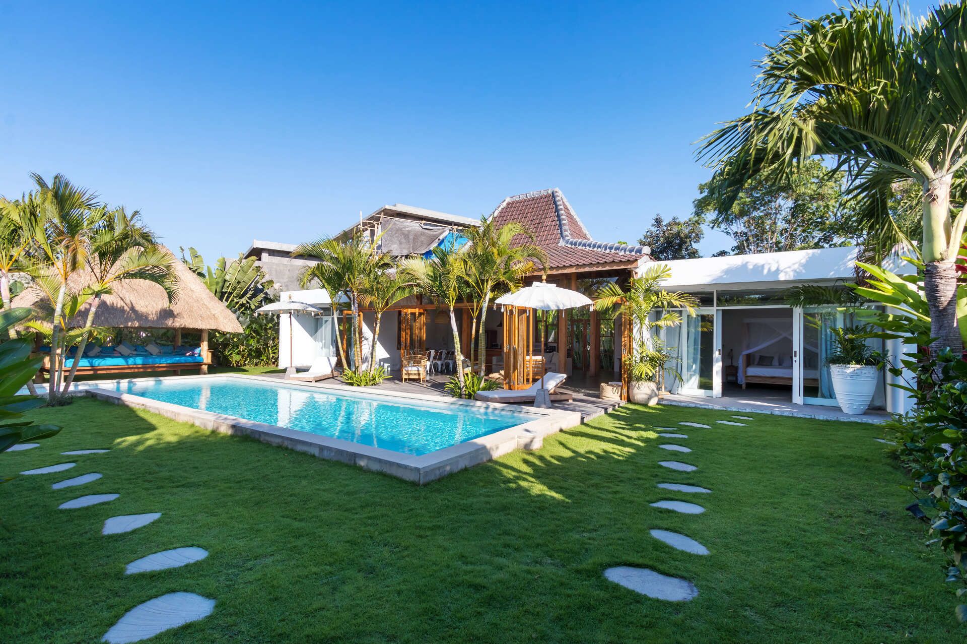 Une villa moderne dotée d’une piscine, d’un espace extérieur aménagé et d’une végétation luxuriante.