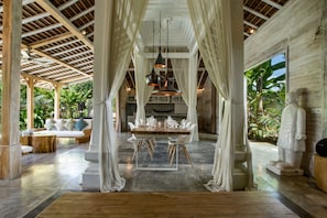 A spacious dining area with a high ceiling, wooden beams, and a large table set for a meal.