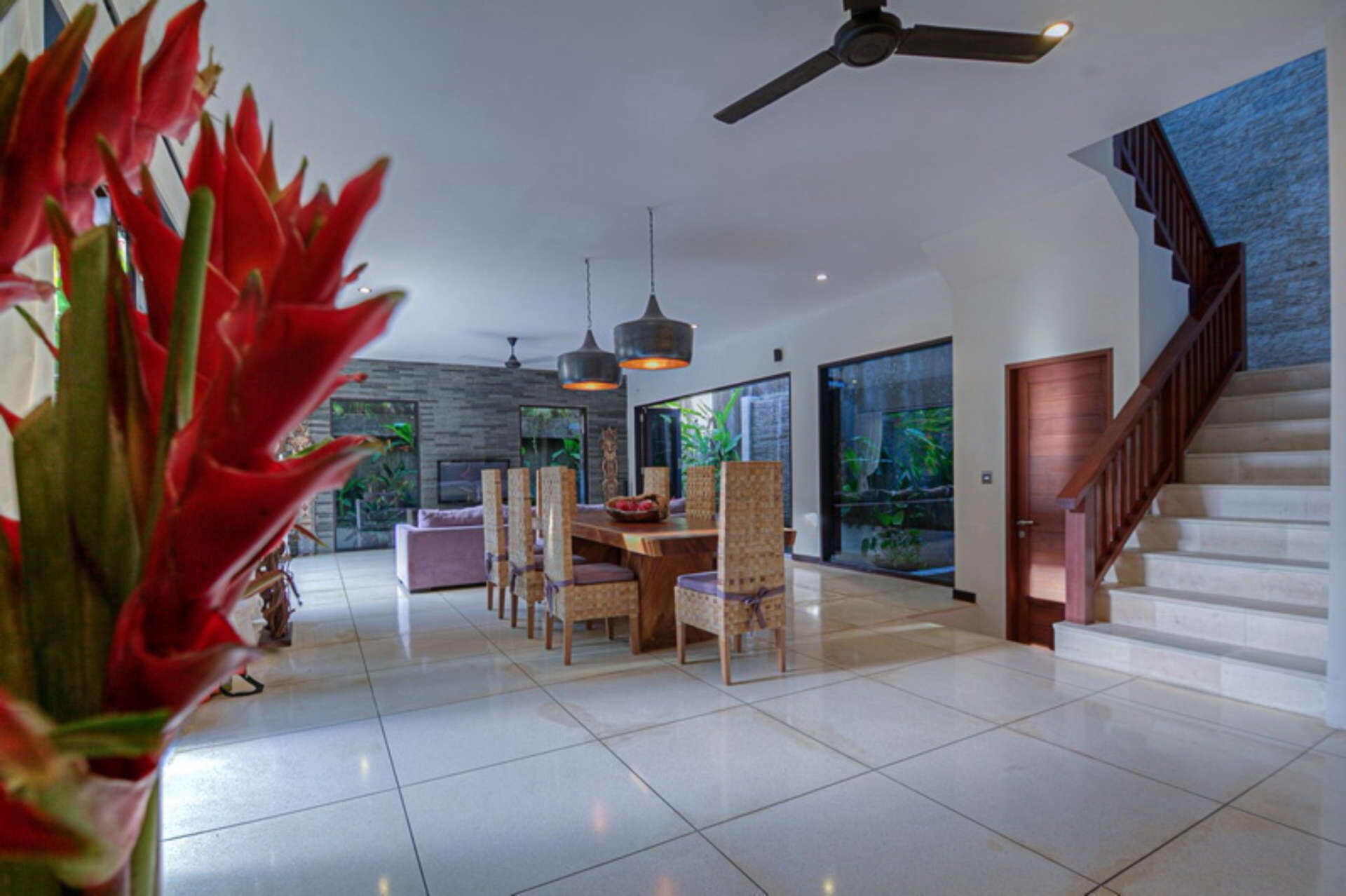 A spacious living room with a dining area, a staircase, and a large window with a view of greenery.