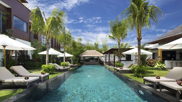 A pool with clear water, surrounded by lounge chairs and umbrellas, with a building on each side. - Bali Villa Near the Beach, 2061 (Seminyak)
