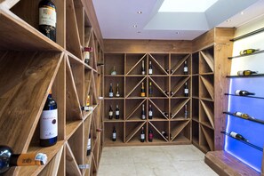 Wine bottles are displayed on a geometric shelving system, surrounded by ample lighting and stone flooring.