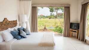 Een slaapkamer met een groot bed, een televisie en uitzicht op een rijstveld.