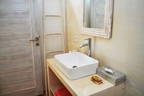 A bathroom with a white sink, a mirror, and a door.