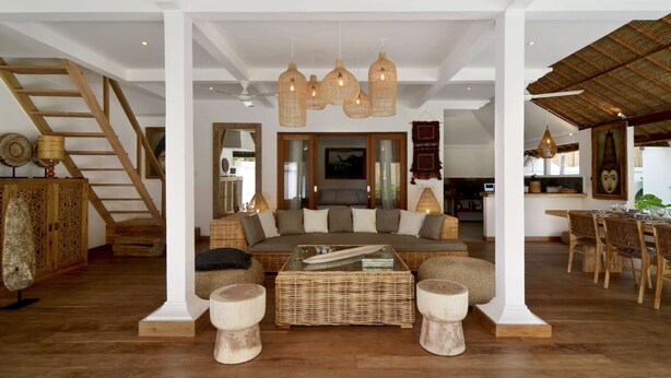 A spacious living area with a large sofa, wicker furniture, and a dining area with wooden chairs and a table. - Villa for Rent in Bali 2039 (Seminyak)