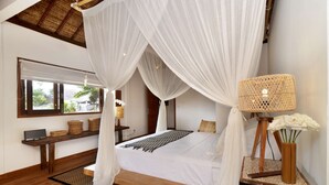 A bedroom with a canopy bed, a bedside lamp, and a view of the outdoors through a window. - Villa for Rent in Bali 2039 (Seminyak)