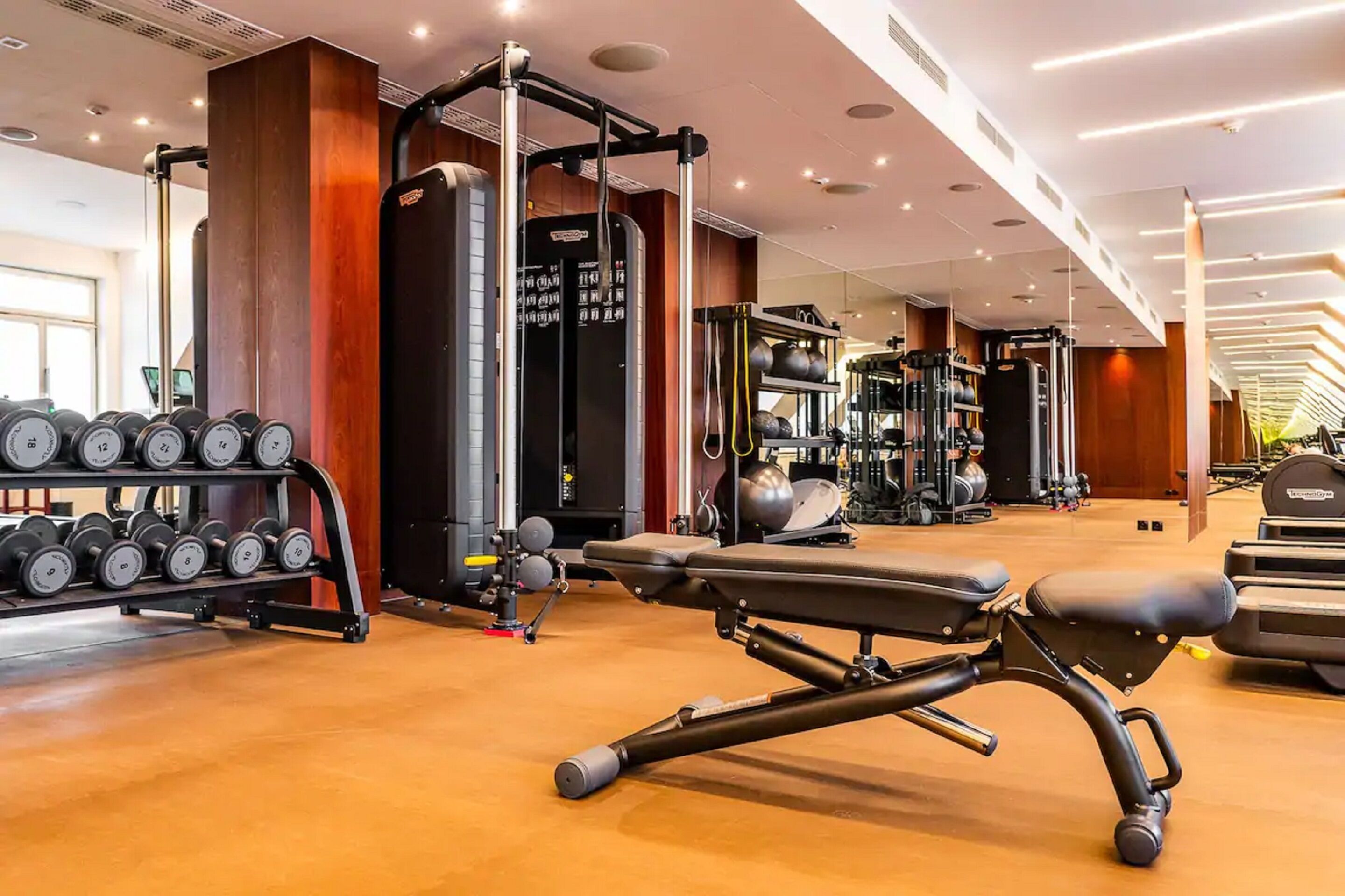 A gym with weightlifting equipment, benches, and dumbbells.