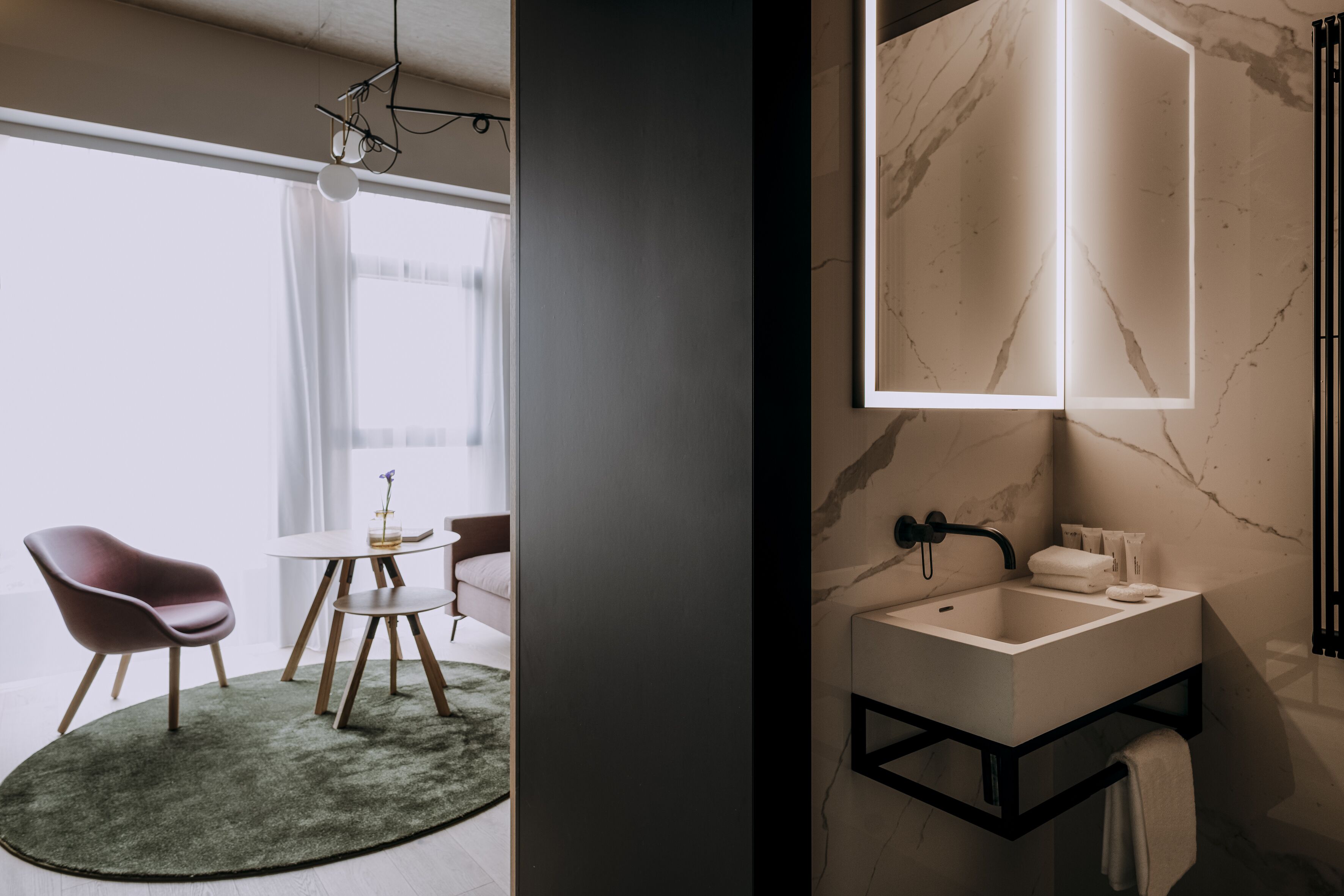 A modern bathroom with a marble sink, a black faucet, and a towel rack.