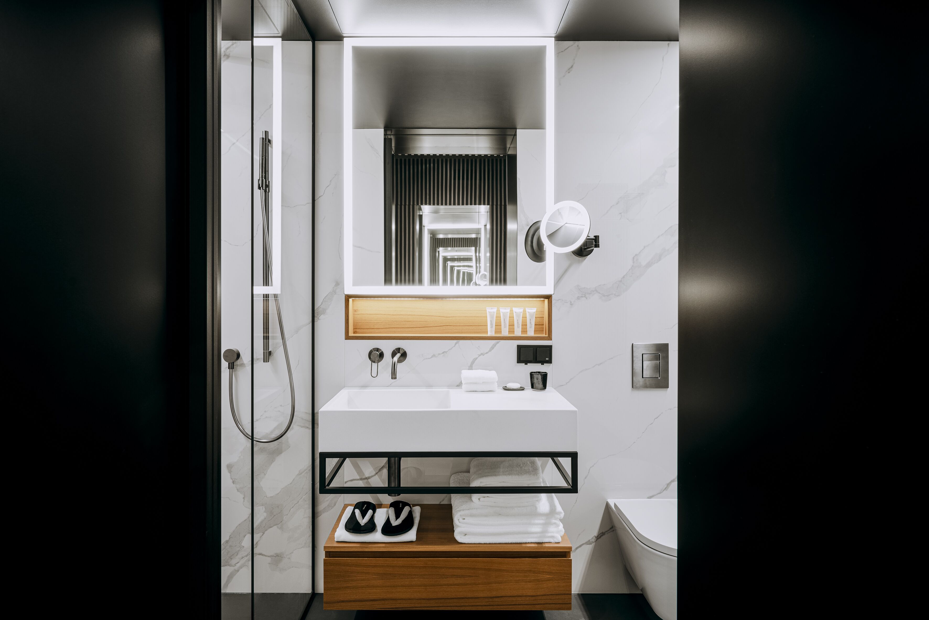 A modern bathroom with a white sink, wooden vanity, and a glass-enclosed shower.
