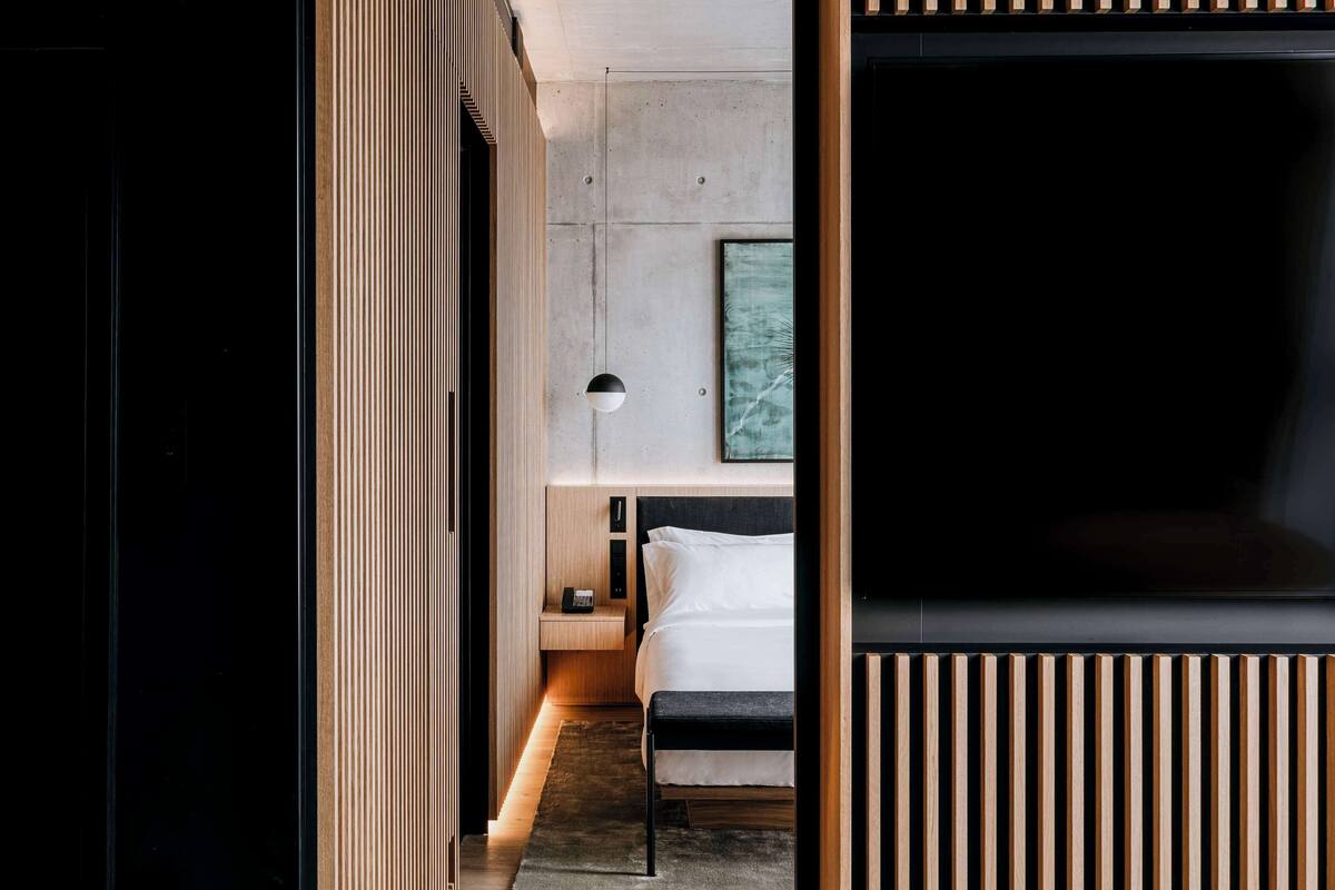 A modern hotel room with a bed, bedside table, and a wall-mounted TV.