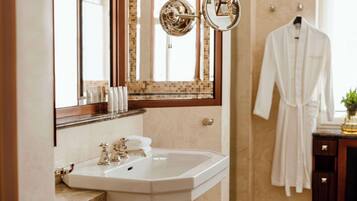 A bathroom with a white sink, a mirror, and a robe hanging on the wall.