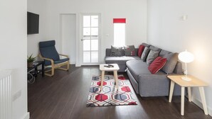 A modern living room with a grey sofa, blue armchair, and a patterned rug. - Sunny Terrace (Maidstone)