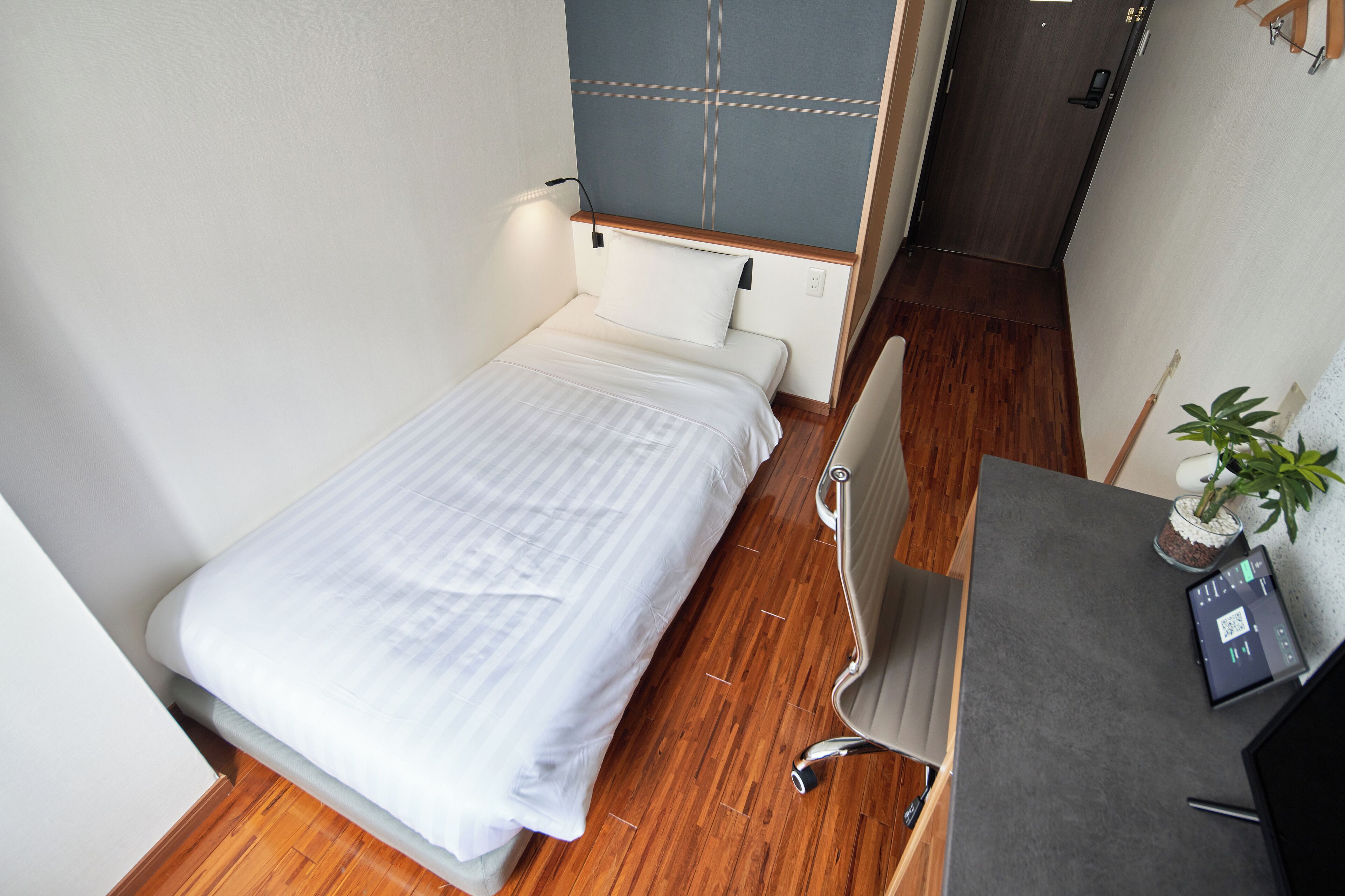 Une petite pièce, bien rangée, avec un lit, un bureau et une chaise.