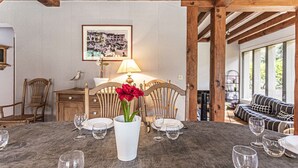 Een eetruimte met een tafel voor zes personen, een vaas met rode bloemen en een lijst met een afbeelding aan de muur.