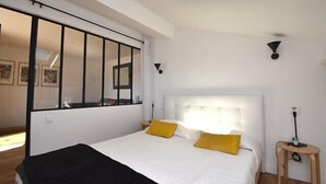 A bedroom with a large bed, a skylight, a bedside table, and a window with blinds. - Hossegor “Côte d’Argent”, Apartment on the edge of the lake for 2 people. (HOSSEGOR)