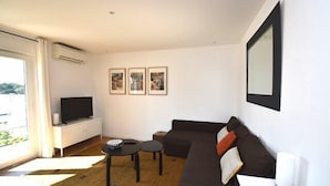 A modern living room with a sofa, a TV, and three framed pictures on the wall. - Hossegor “Côte d’Argent”, Apartment on the edge of the lake for 2 people. (HOSSEGOR)