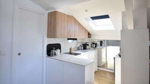 A modern kitchen with white cabinetry, a skylight, and a view to the dining area. - Hossegor “Côte d’Argent”, Apartment on the edge of the lake for 2 people. (HOSSEGOR)