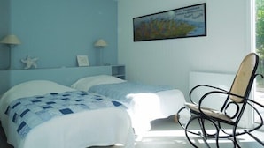 Une chambre avec deux lits, une chaise et un tableau au mur.