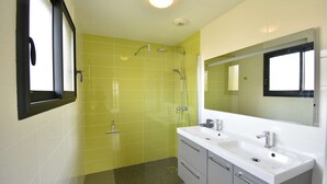 Een badkamer met gele tegels, een witte wastafel en een grote spiegel.