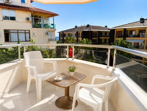 A balcony with white plastic chairs, a small table, and a potted plant. - Yaman Life Hotel (Alanya)