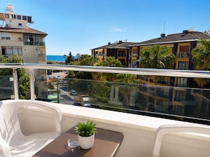 A balcony with a table, chairs, and a potted plant.
