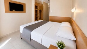 A hotel room with a bed, a TV mounted on the wall, a wardrobe, and a bedside table with a plant. - Yaman Life Hotel (Alanya)