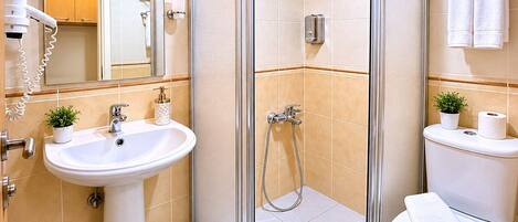 Un baño moderno con ducha de vidrio, lavamanos y retrete.