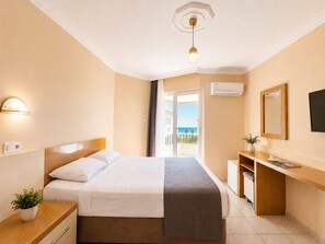 A hotel room with a bed, bedside table, desk, and a view of the sea through a balcony door. - Yaman Life Hotel (Alanya)