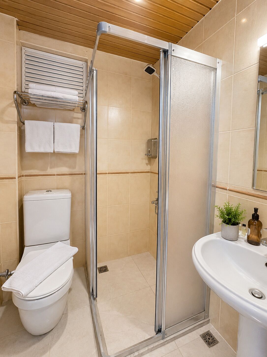 A bathroom with a shower enclosure, toilet, sink, and towel rack.