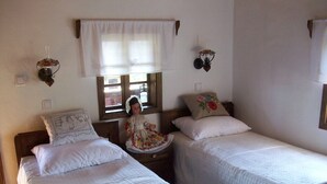 A room with two single beds, a wooden headboard, a window with a white valance, and a wall-mounted lamp. - Ethno Village Stara Lonja (Sisak)
