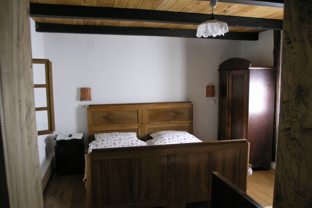 A wooden bed with a simple headboard, a small bedside table, and a nightstand.