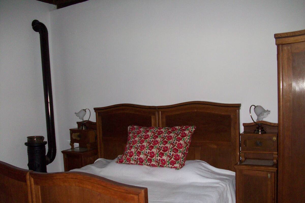 A bedroom with a wooden bed, a nightstand, a bedside table, and a wardrobe.