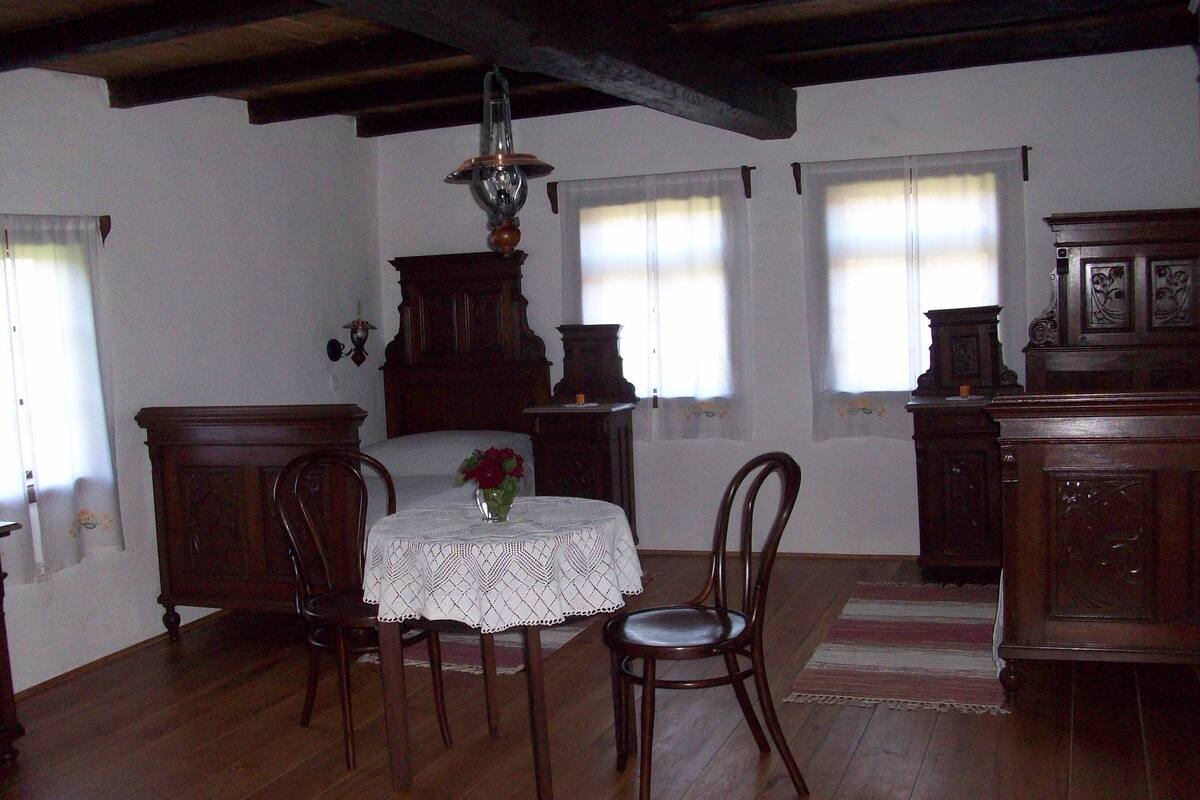 A dining area with a wooden table, chairs, and a vase of flowers.