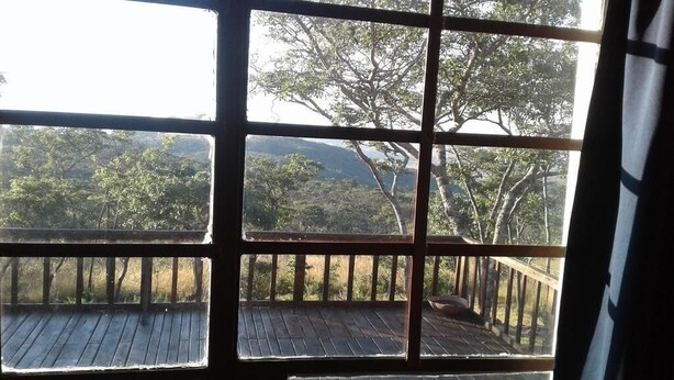 Una habitación con un ventanal grande dividido en nueve secciones, que ofrece vistas a un paisaje boscoso con árboles y colinas.