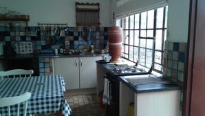Una cocina con salpicadero de azulejos, estufa a gas, pileta y ventana que proporciona luz natural.
