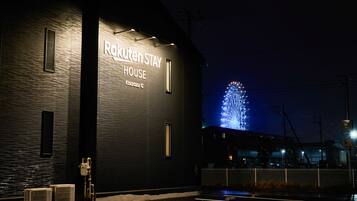 Un edificio con un cartello che riporta "Rakuten Stay House" e una grande struttura illuminata sullo sfondo.