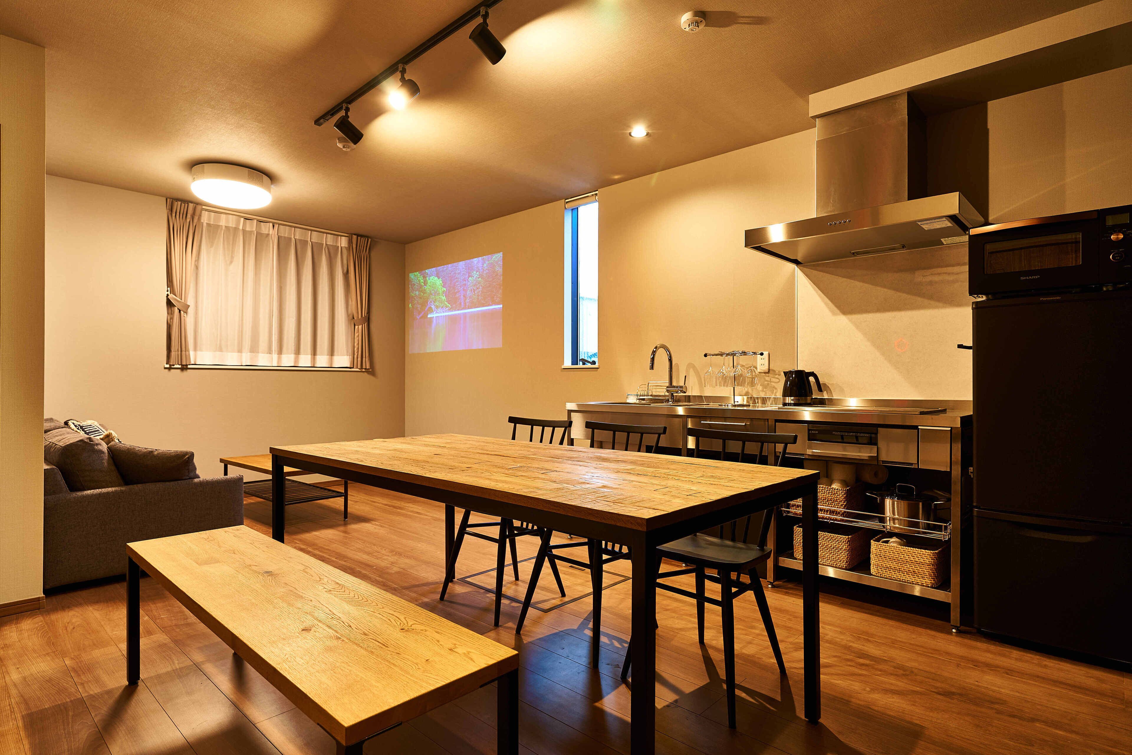 A modern kitchen with a wooden dining table, chairs, and a built-in oven.