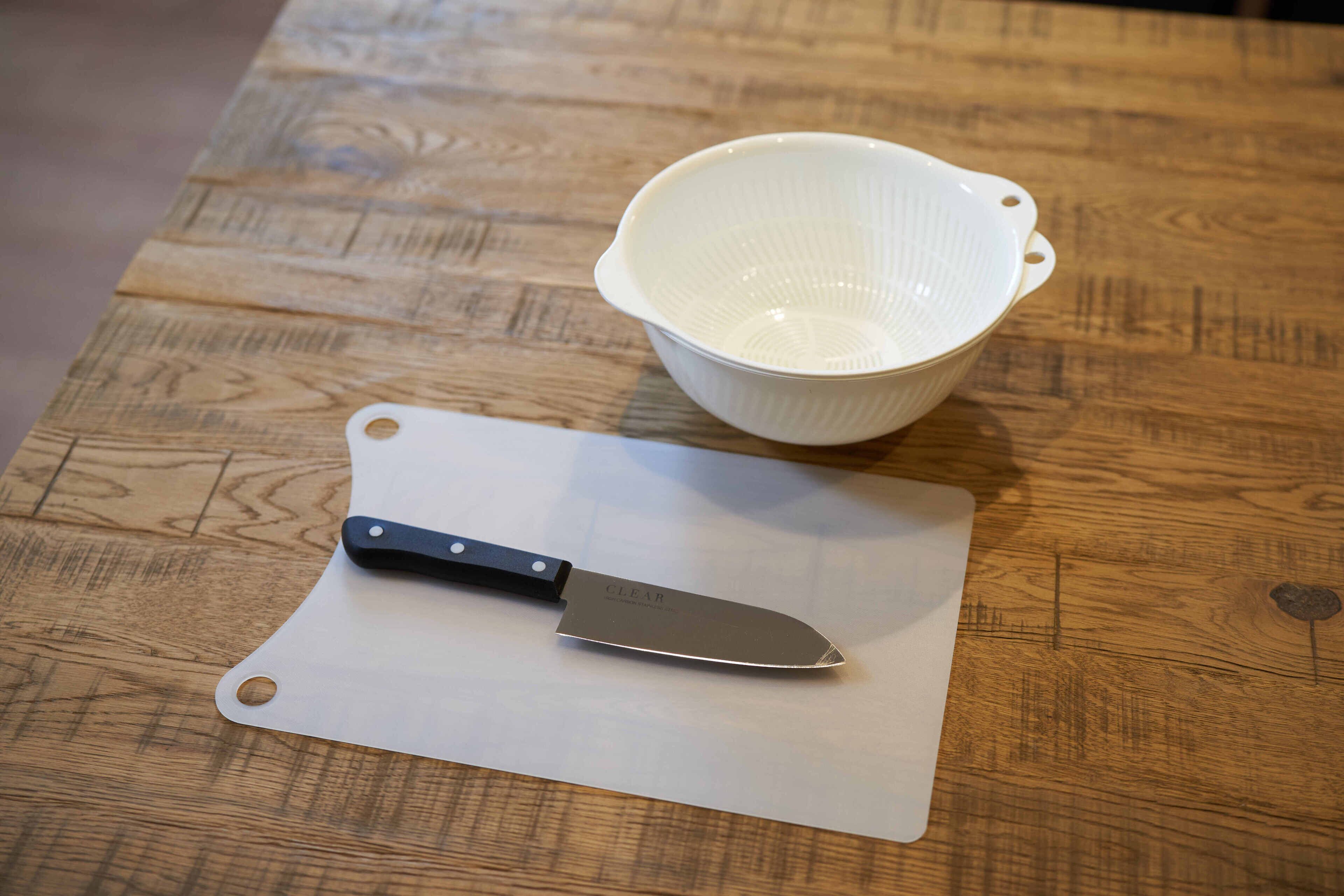 A wooden table with a white cutting board and a knife on it.