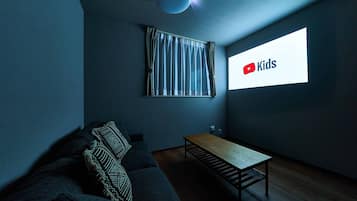 A modern living room with a dark blue sofa, a wooden coffee table, and a large window with a curtain.