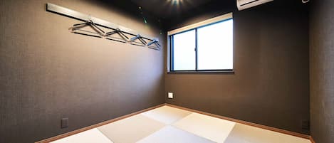 A room with tatami mats, a window, and an air conditioning unit.
