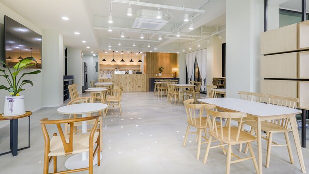 A spacious, well-lit dining area with multiple tables and chairs, a central counter, and a modern kitchen in the background. - Swimeong Nolmeong Guesthouse&Pension (Jeju City)